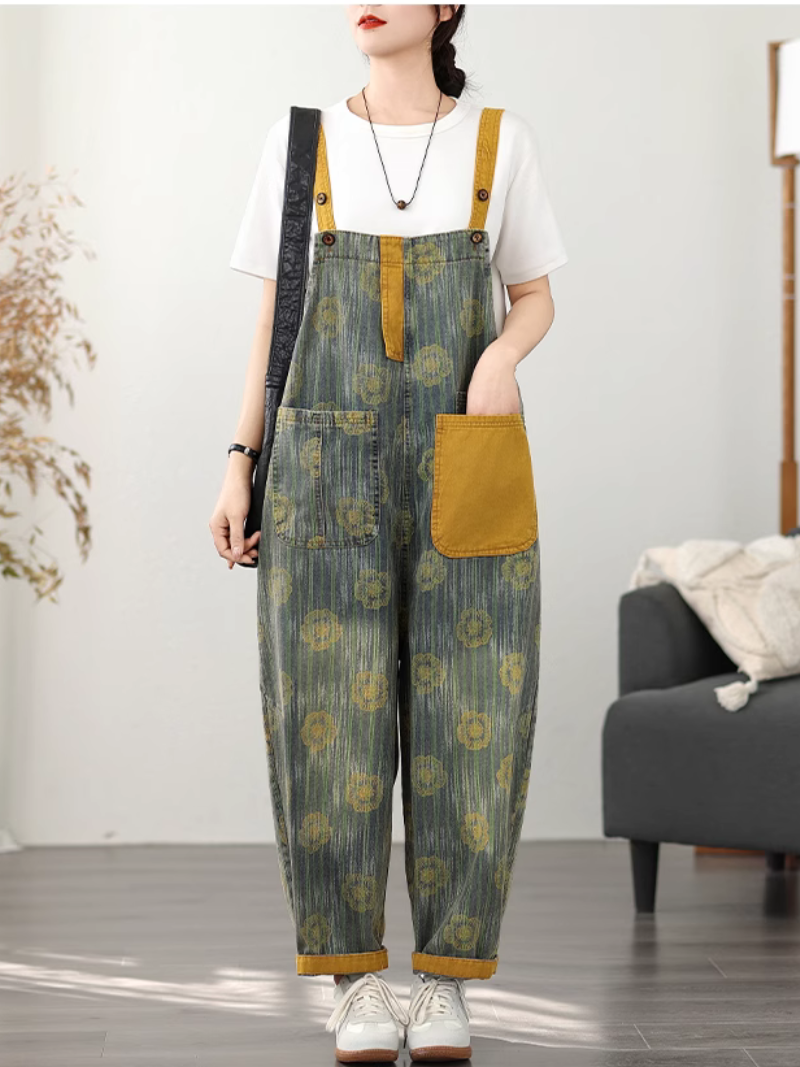 A woman wearing vintage-inspired printed dungarees with adjustable straps, paired with a white shirt and carrying a bag.
