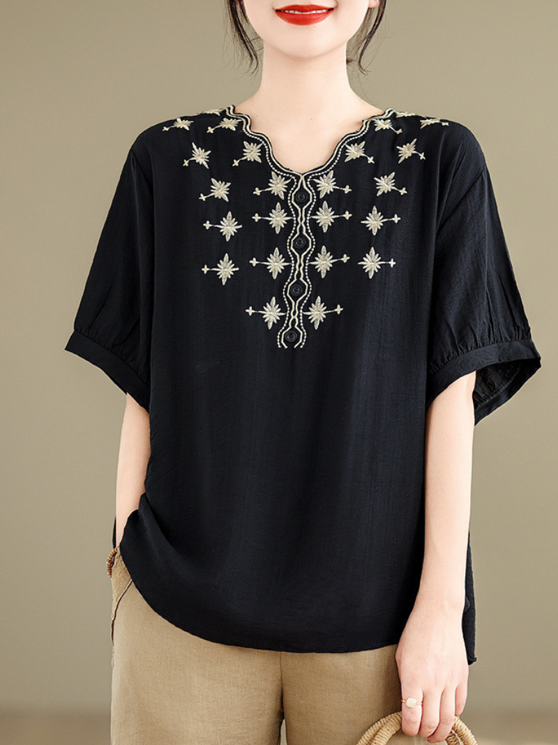 A woman wearing a  loose t-shirt top with embroidery around the neckline and three-quarter sleeves