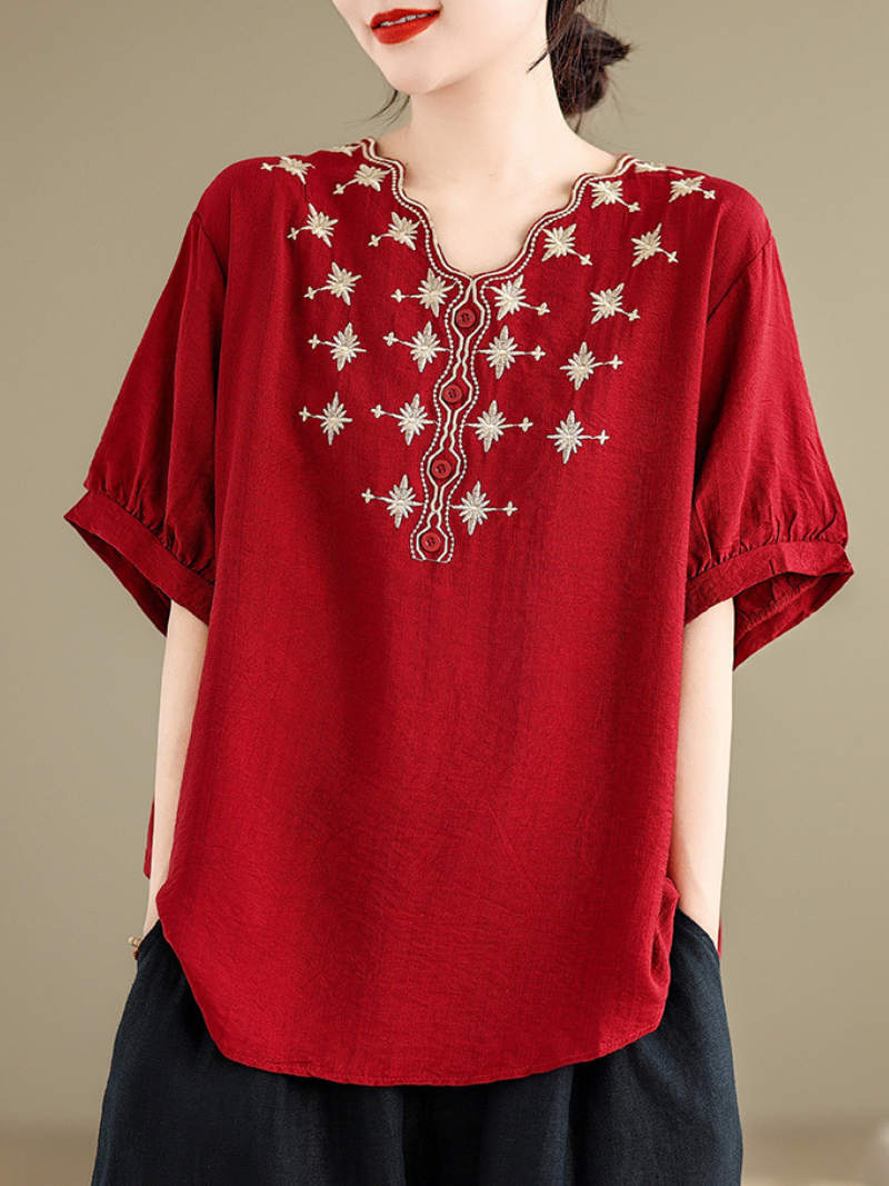 A woman wearing a Red loose t-shirt top with embroidery around the neckline